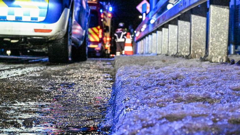 09.01.2026, Bayern, Freising: Ein Polizeiwagen steht auf einer Straße, deren Rand mit Eis überzogen ist. 