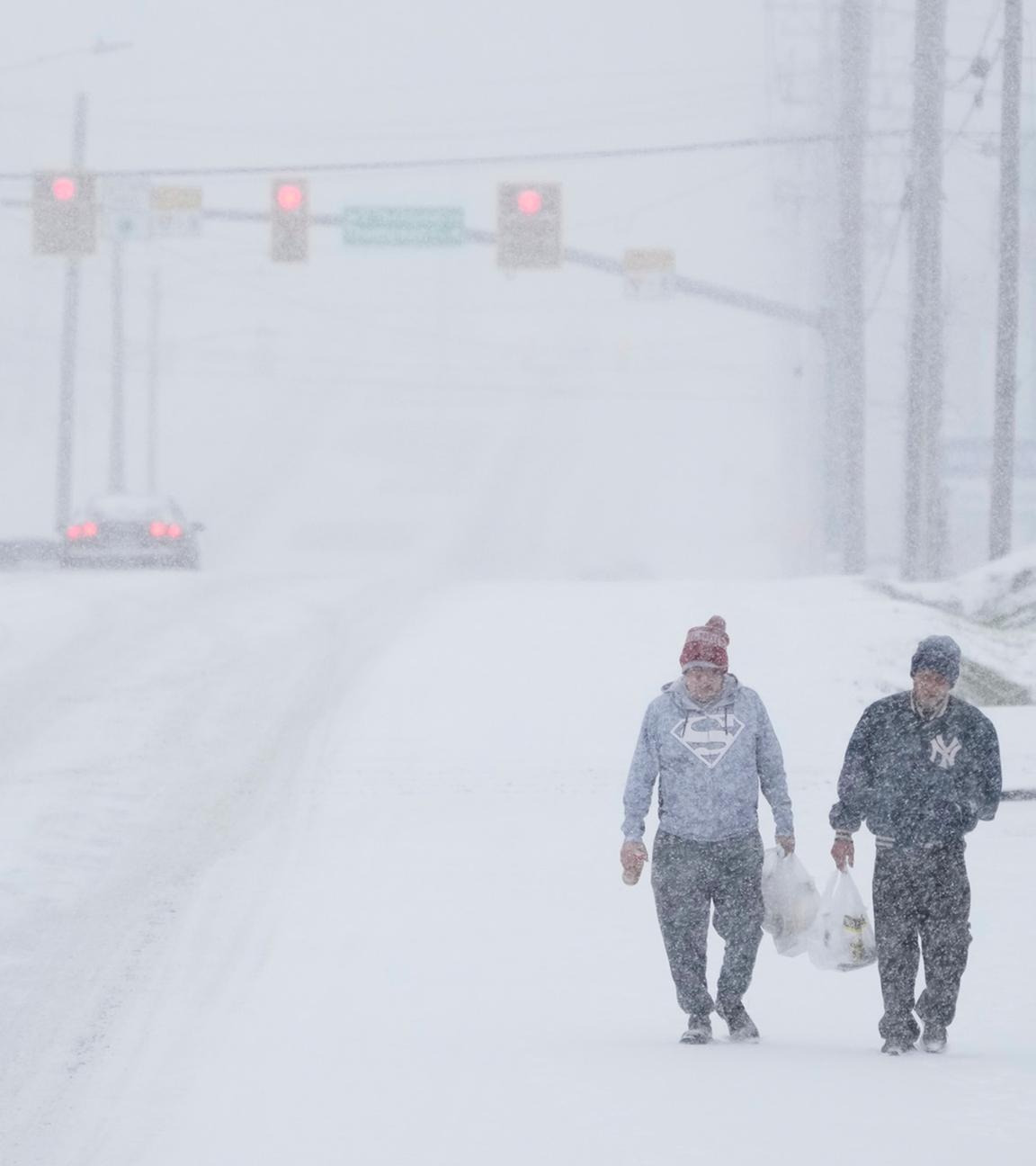 Menschen laufen in Nashville, Tennessee mit ihren Einkäufen durch den Schneesturm.