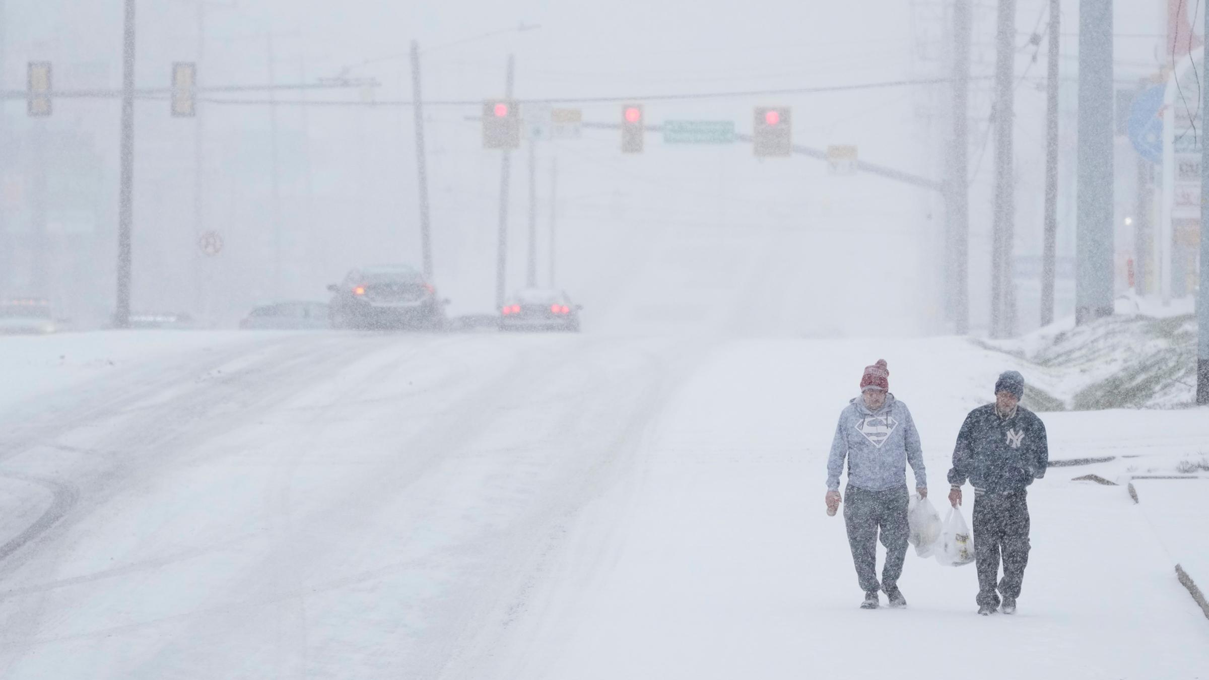 Menschen laufen in Nashville, Tennessee mit ihren Einkäufen durch den Schneesturm.