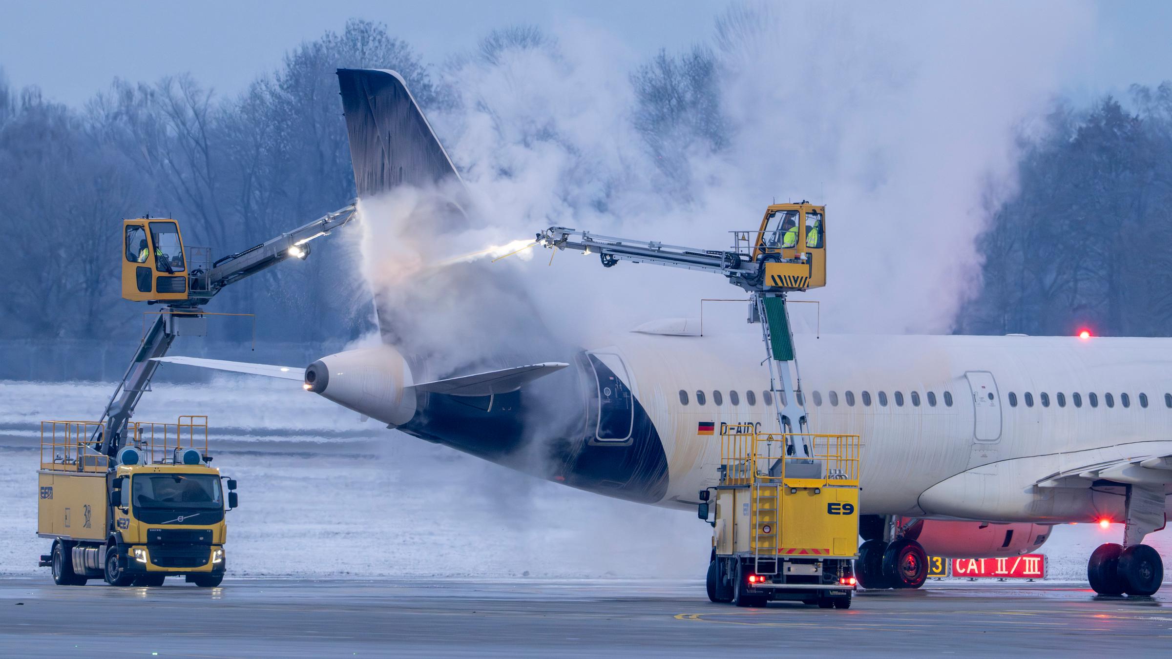 Am Flughafen München wird in den frühen Morgenstunden ein Flugzeug der Airline Lufthansa auf einer Enteisungsfläche von Spezialfahrzeugen am 12.01.2026 enteist.