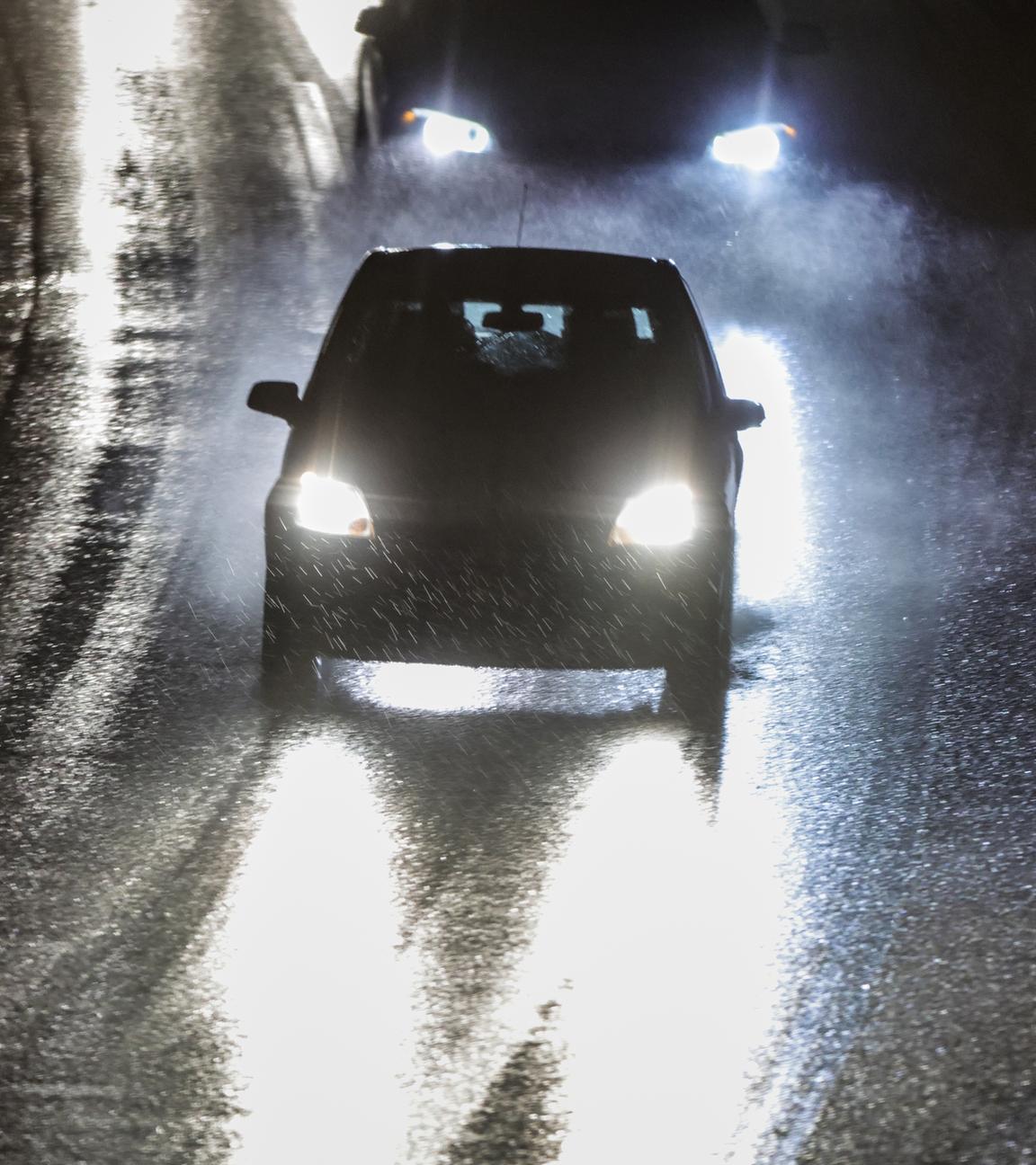 Fahrzeuge fahren in der Nacht vom 12.01.2026 bei Regen über die Bundesautobahn A59, Fahrspuren auf der vereisten Fahrbahn sind sichtbar.