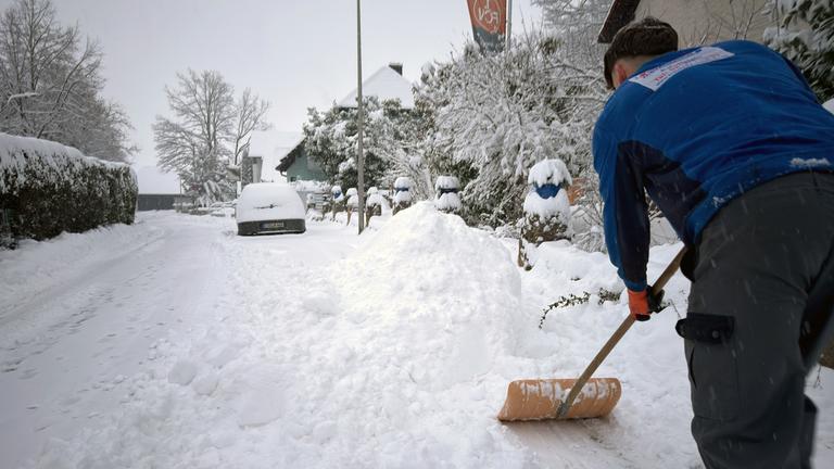 Ein Mann schaufelt im bayerischen Forchheim Schnee von einem Bürgersteig am 26.01.2026.