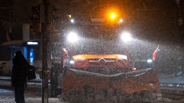 Ein Schneepflug räumt eine Straße in der Innenstadt in München