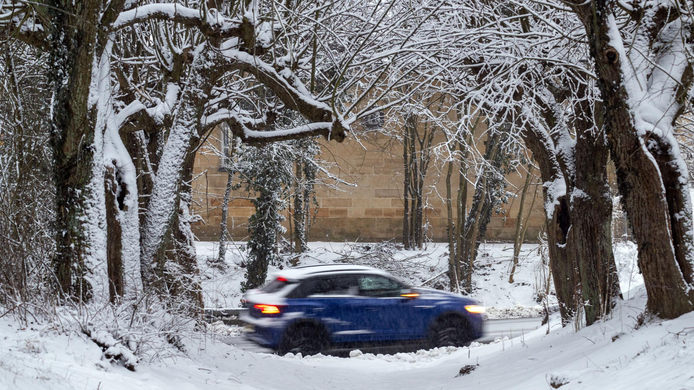 Ein Auto fährt an einer verschneiten Allee mit Bäumen vorbei am 12.01.2026 in Neubanz, , Bayern.