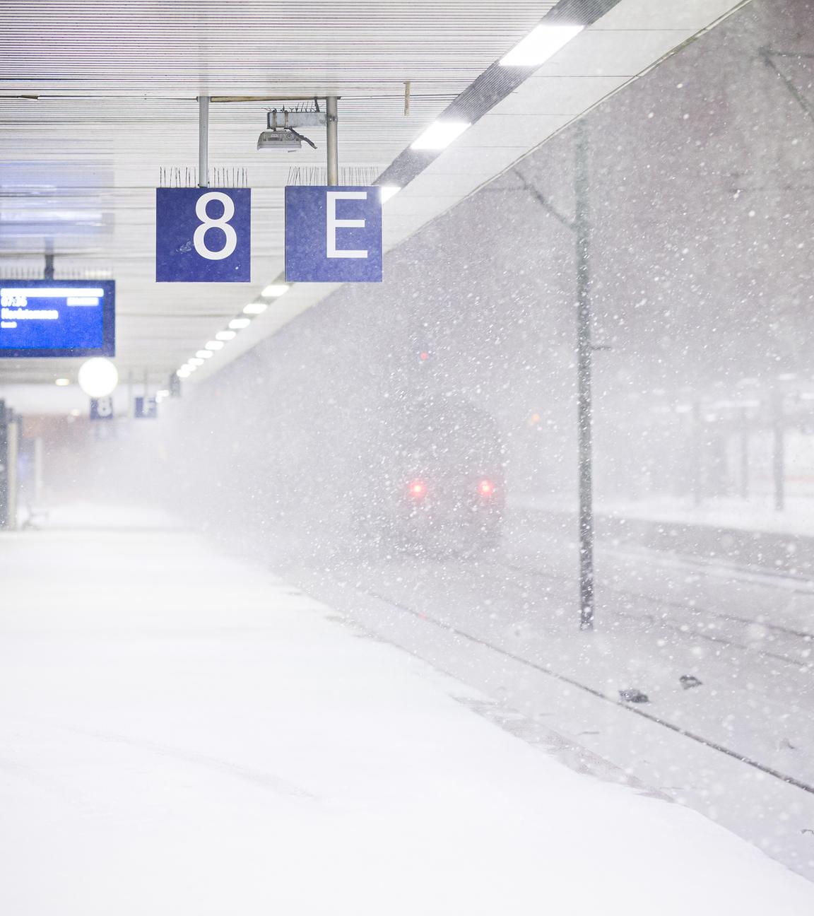 Eine Lok steht am frühen Morgen an einem verschneiten Gleis im Hauptbahnhof.