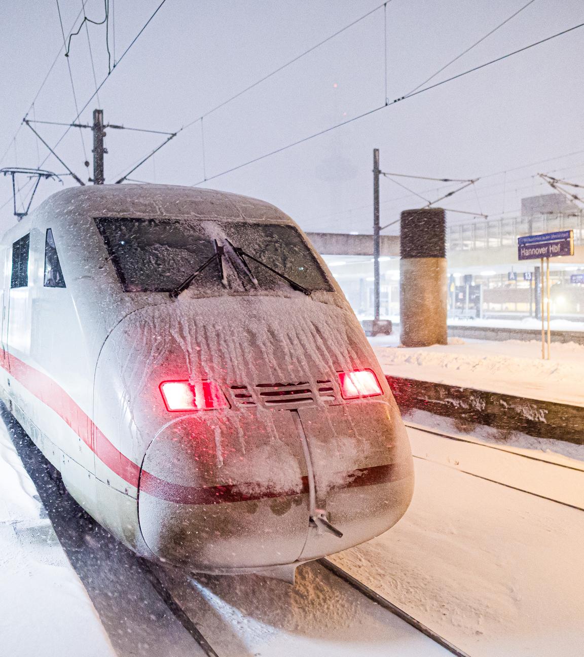 Ein ICE steht am frühen Morgen an einem verschneiten Gleis im Hauptbahnhof. 