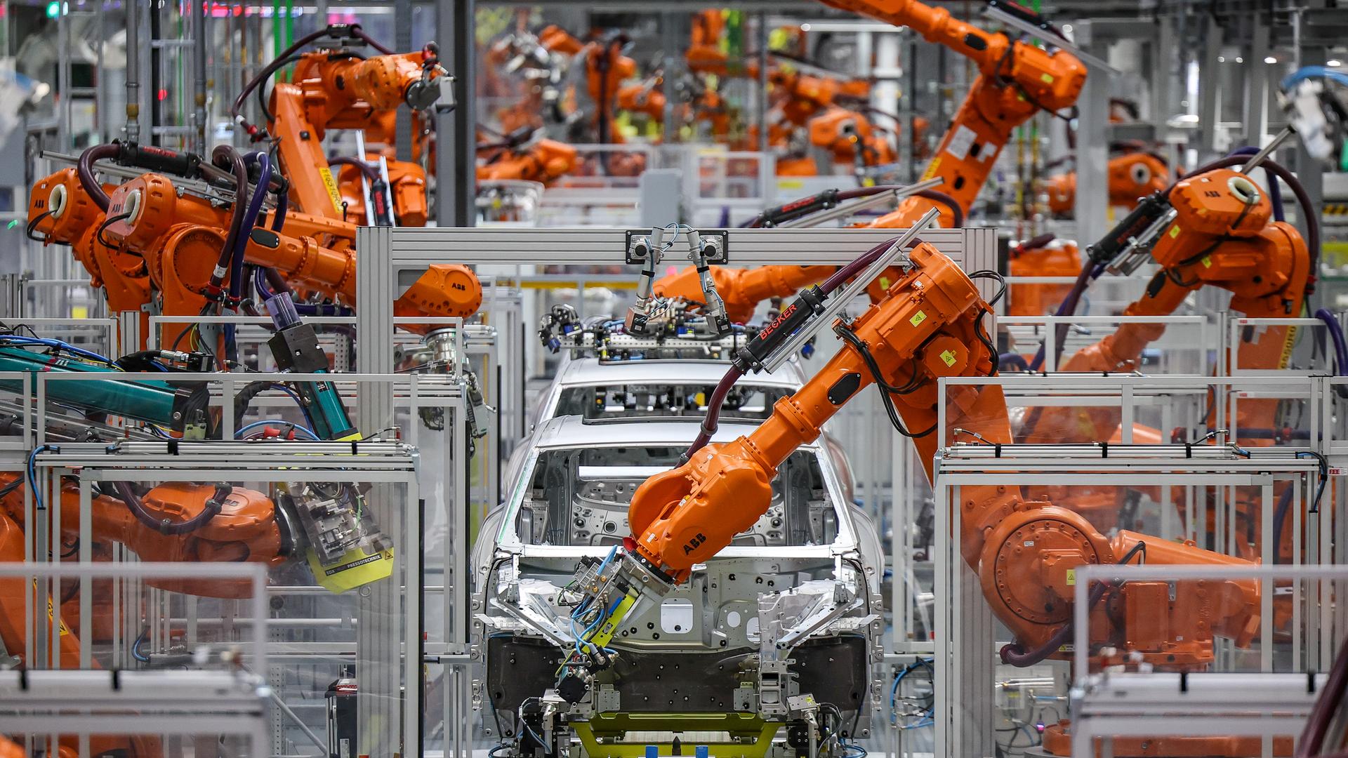 Industrieroboter arbeiten an einer Auto-Karosserie in einer Fabrik.