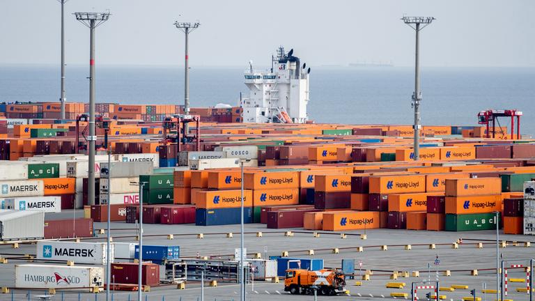 Zahlreiche Container, darunter viele des Logistikunternehmens Hapag-Lloyd, stehen auf dem Terminal von Eurogate auf dem JadeWeserPort nahe der Kaimauer