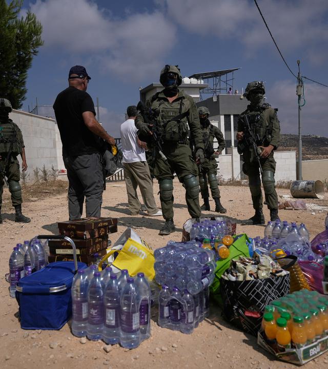 Aktivisten sammeln Lebensmittel- und Wasservorräte vor israelischen Soldaten, die die Straße zu den Häusern von drei palästinensischen Familien blockieren.