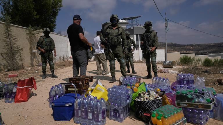 Aktivisten sammeln Lebensmittel- und Wasservorräte vor israelischen Soldaten, die die Straße zu den Häusern von drei palästinensischen Familien blockieren.