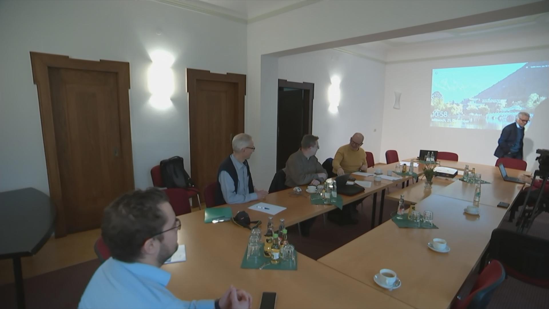 Mehrere Männer sitzen an Konferenztisch