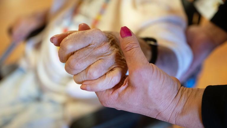 Eine Physiotherapeutin hält die Hand einer Pflegeheimbewohnerin am 07.02.2024 in Filderstadt. 