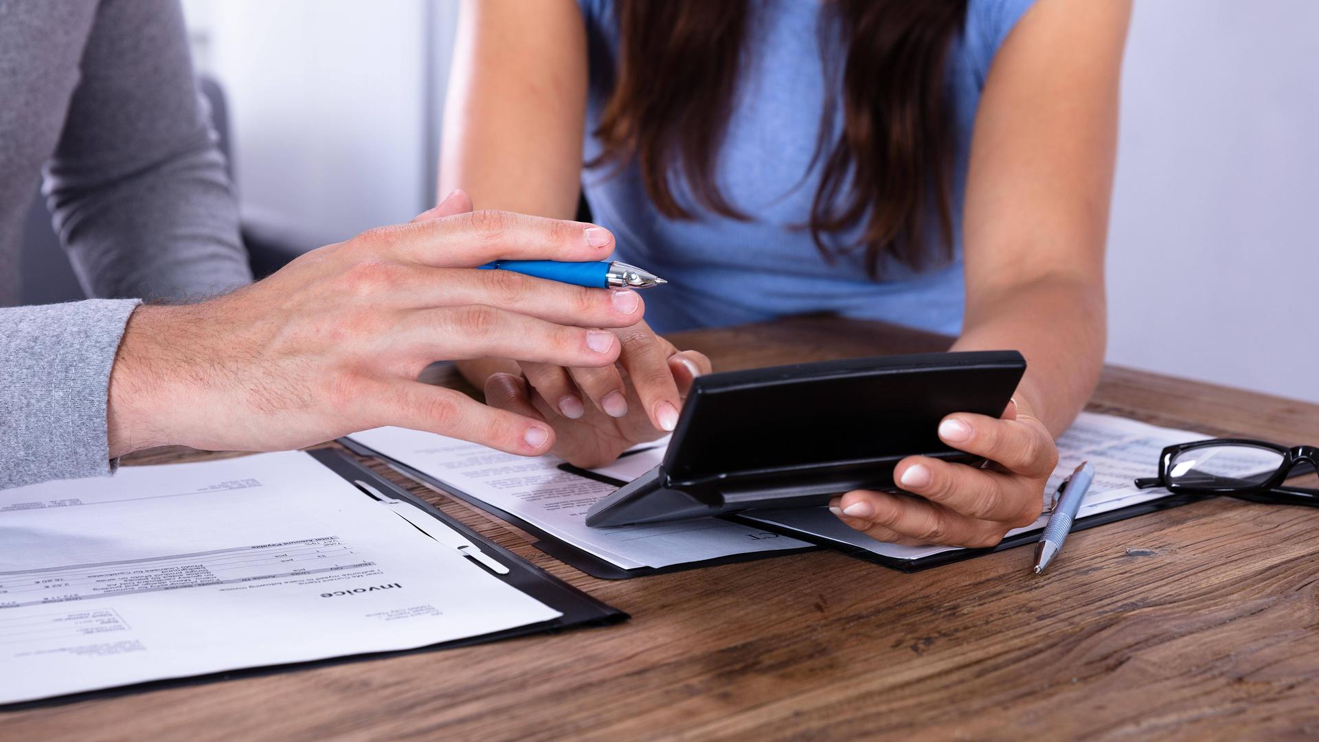 Hände mit Taschenrechner und Stift