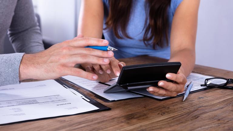 Hände mit Taschenrechner und Stift