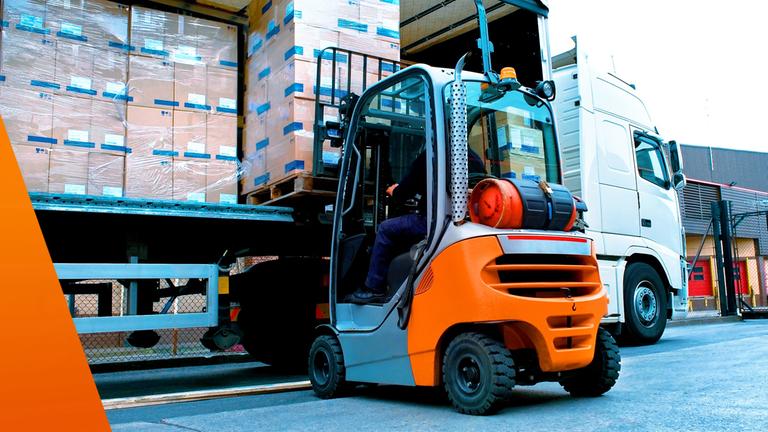 Große Lagerhalle mit Hochregalen. Ein Gabelstapler belädt einen LKW mit Paletten.