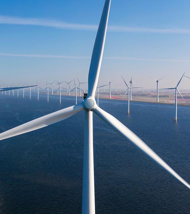 Offshore-Windpark im Meer. Im Hintergrund ist die Küste zu sehen.