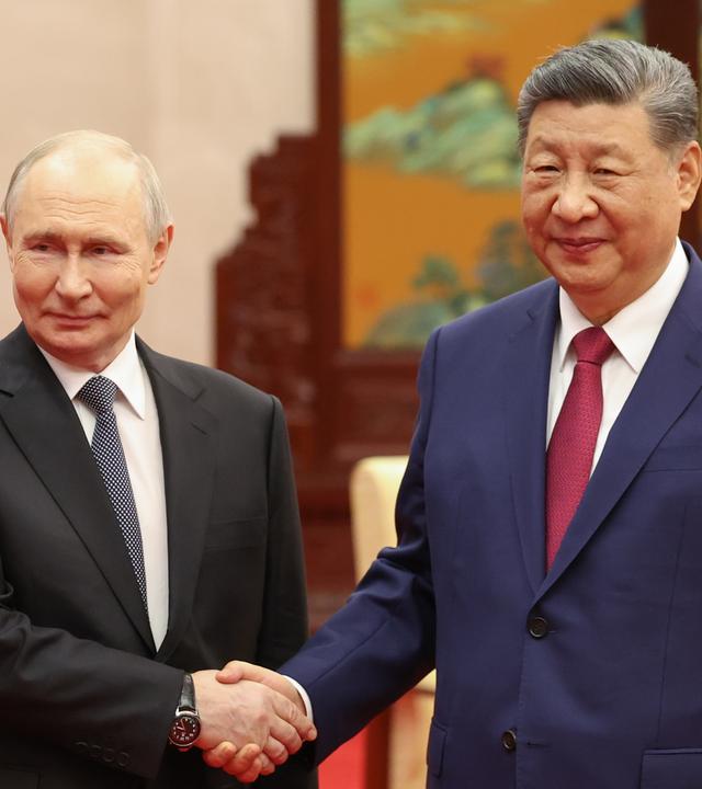 Wladimir Putin (l.), Präsident Russlands, und sein Amtskollege Xi Jinping aus China geben sich während eines informellen Teetreffens in der Großen Halle des Volkes die Hand.