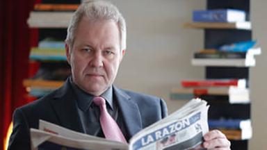 Wladislaw Inosemzew sitzt an einem Tisch und hält die Zeitung La Razon aufgeschlagen in der Hand.