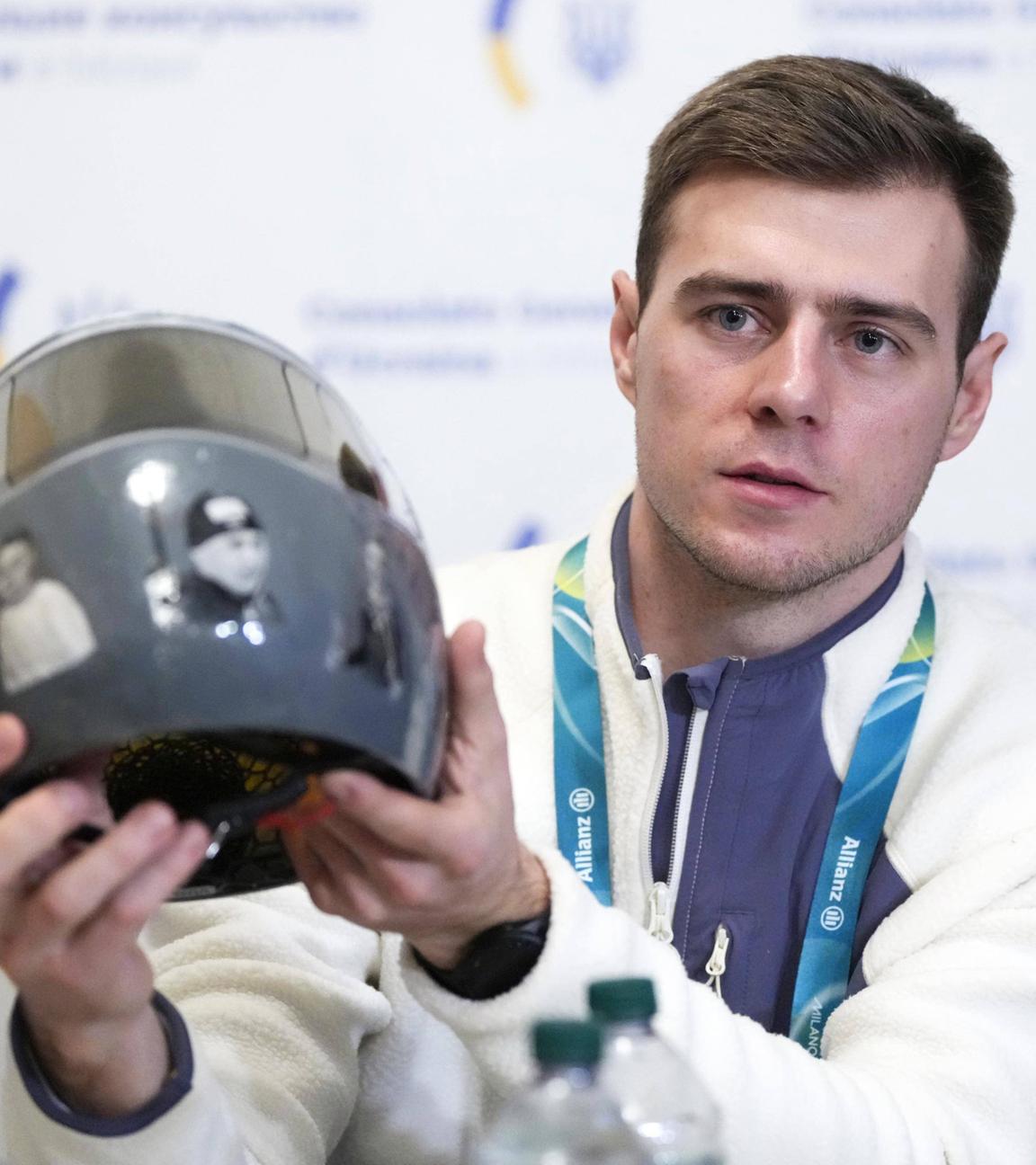 Der ukrainische Skeletonfahrer Wladyslaw Heraskewytsch zeigt bei einer Pressekonferenz zu den Olympische Winterspielen 2026 seinem Helm mit Erinnerungsbildern von getöteten ukrainischen Sportlern