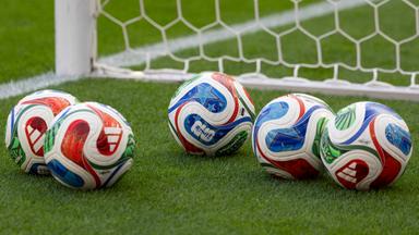 5 Adidas Baelle (Ball) Trionda fuer die Fussball WM 2026, auf dem Rasen liegend, vor dem Tornetz