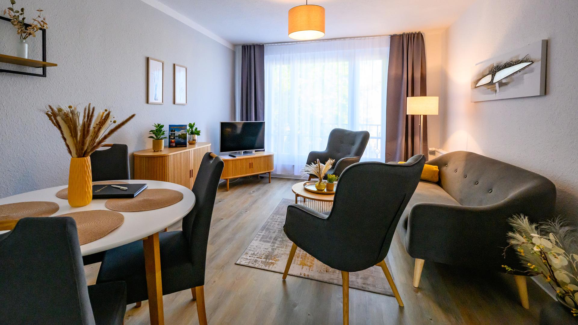 Simpel möblierter Wohnraum mit Essbereich, Couch, Sesseln und Fernseher