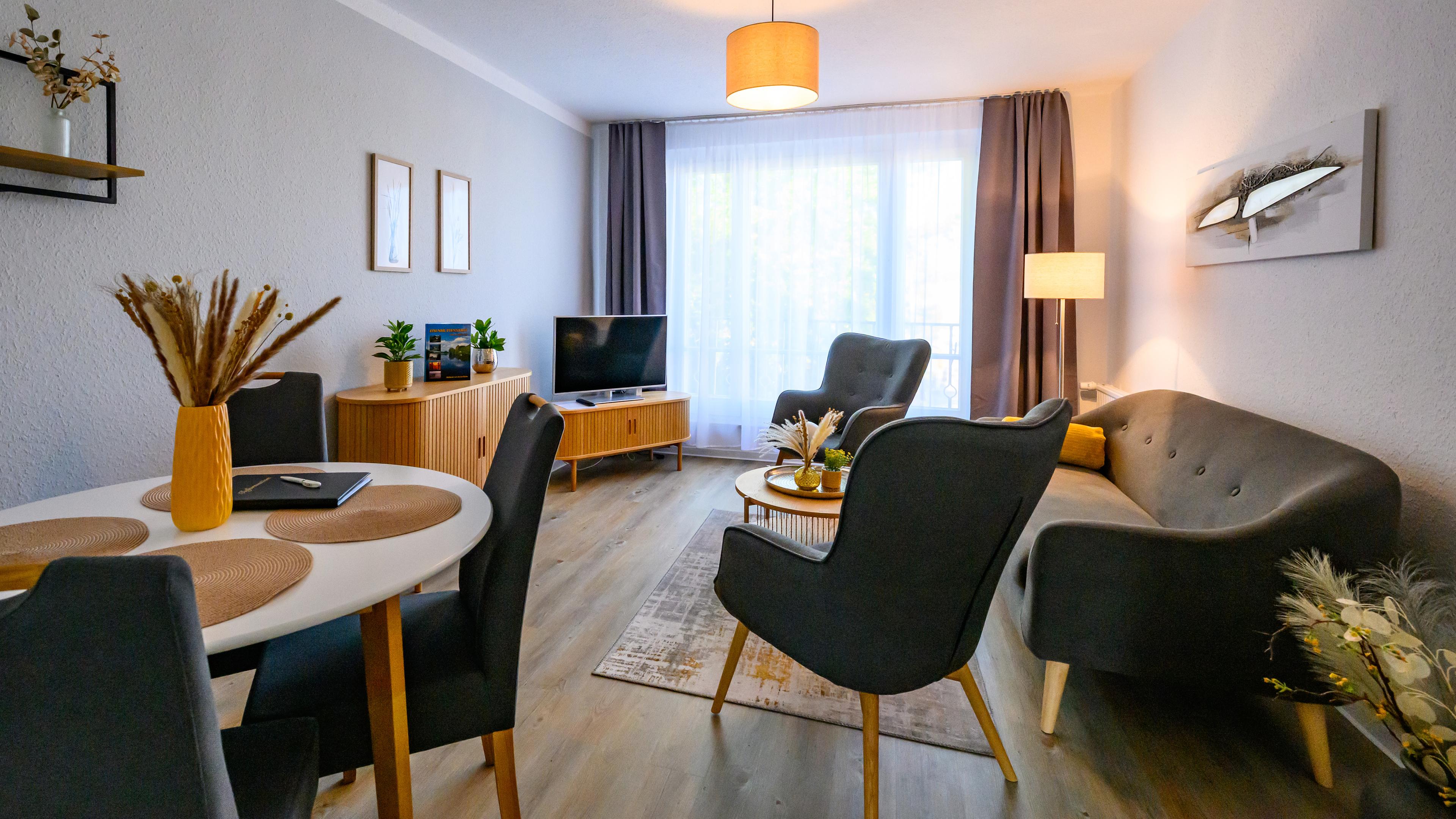 Simpel möblierter Wohnraum mit Essbereich, Couch, Sesseln und Fernseher