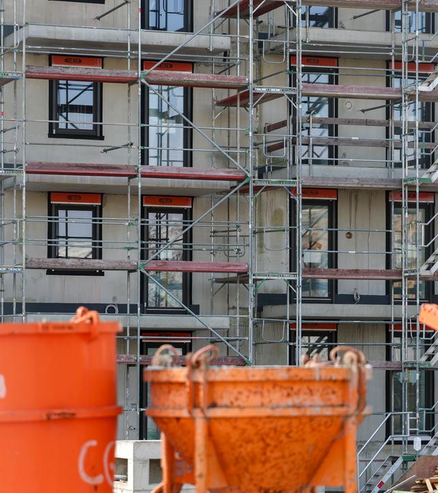 Baugeräte stehen auf einer Baustelle für neue Wohnhäuser.