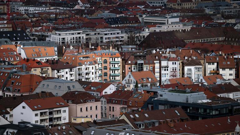 Vereinzelte Gebäude werden in der Stuttgarter Innenstadt durch ein Wolkenloch von der Sonne angestrahlt.