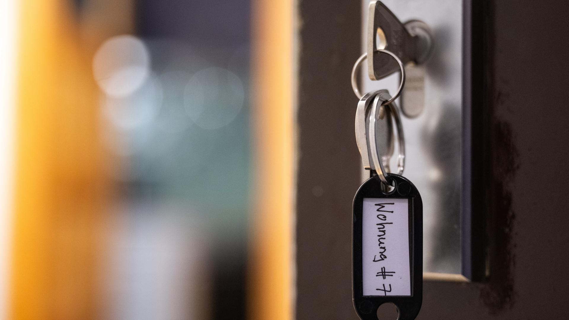 Symbolbild: Ein Schlüssel mit der Aufschrift «Wohnung #7» hängt an einer Wohnungseingangstür.