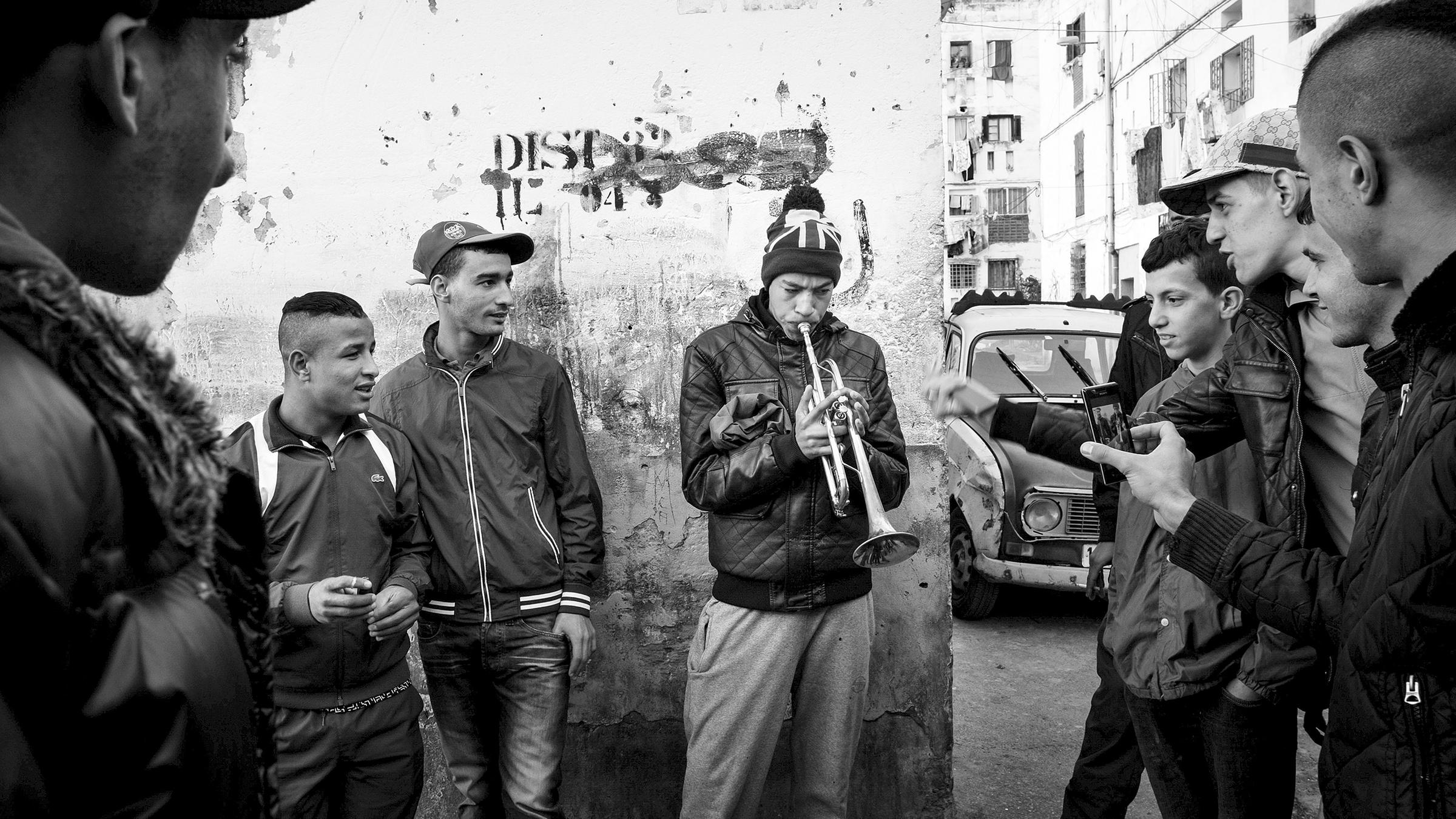 Algerien, Alger: Ein junger Mann hat Publikum, während er im überfüllten Viertel "climat de france" mit einer Trompete experimentiert.