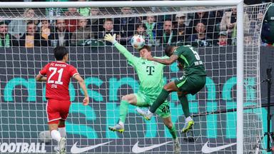 Mittelfeldspieler Vinícius Souza vom VfL Wolfsburg köpft den Ball aufs Tor, doch Torwart Jonas Urbig vom FC Bayern kann parieren.