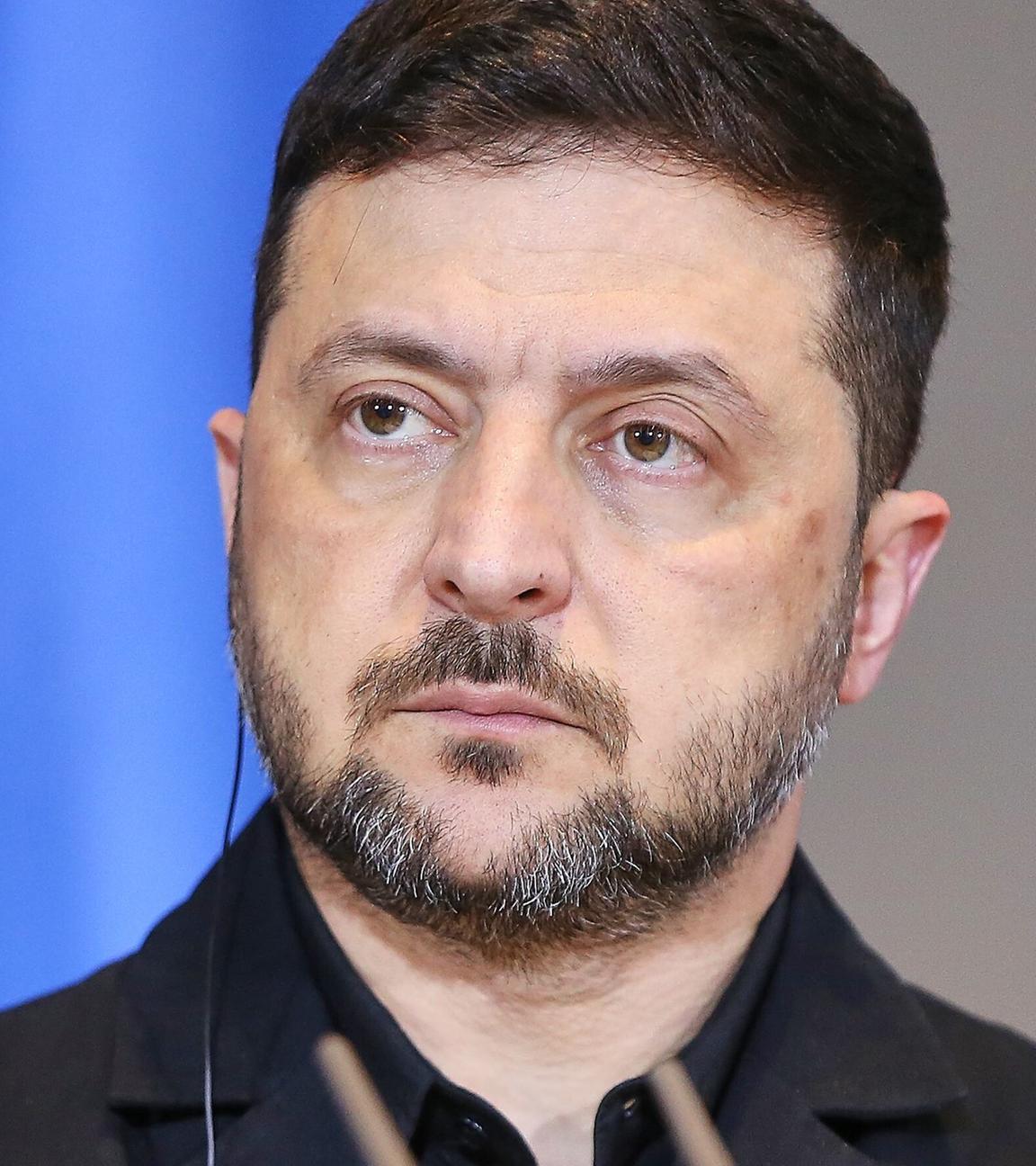 Ukraines Präsident Wolodymyr Selenskyj vor einer abgeschnittenen Fahne der Ukraine.