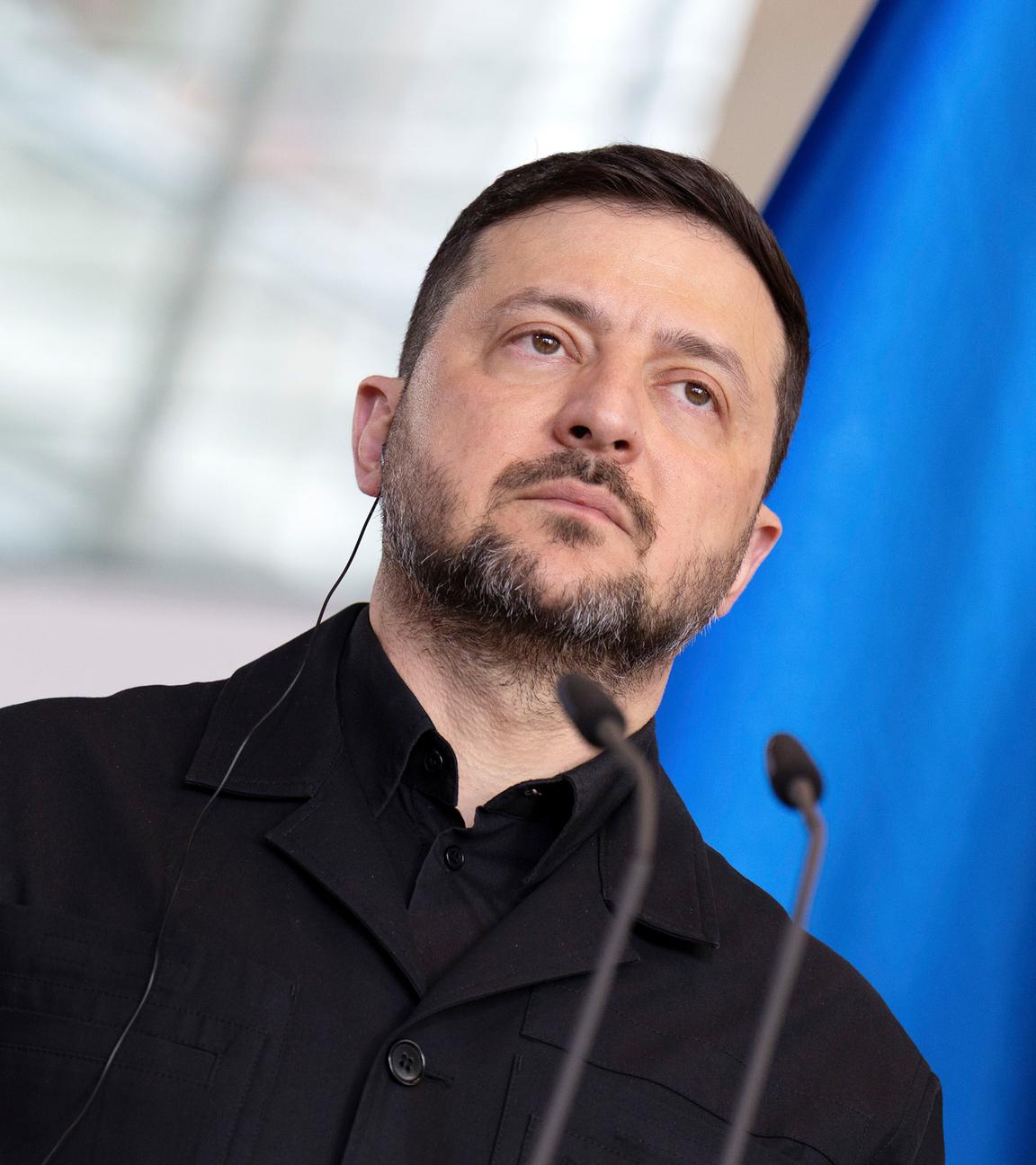 Wolodymyr Selenskyj steht vor einem Mikrofon-Pult. Im Hintergrund ist due Flagge der Europäischen Union zusehen.