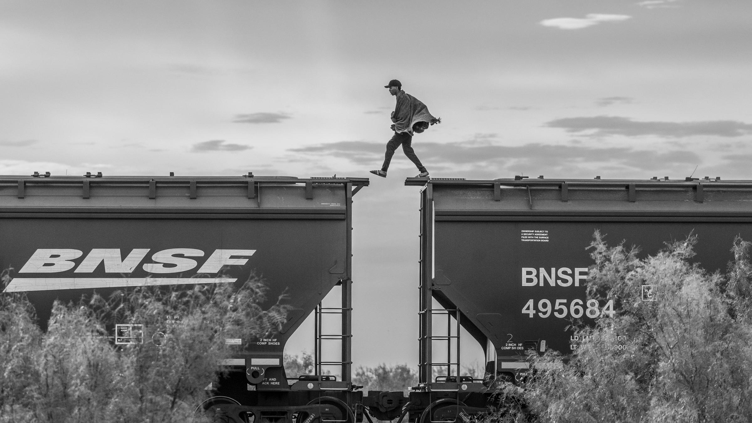 Ein Migrant läuft auf einem Frachtzug in Mexiko und überquert gerade die Lücke zwischen zwei Waggons. (8. Oktober 2023)