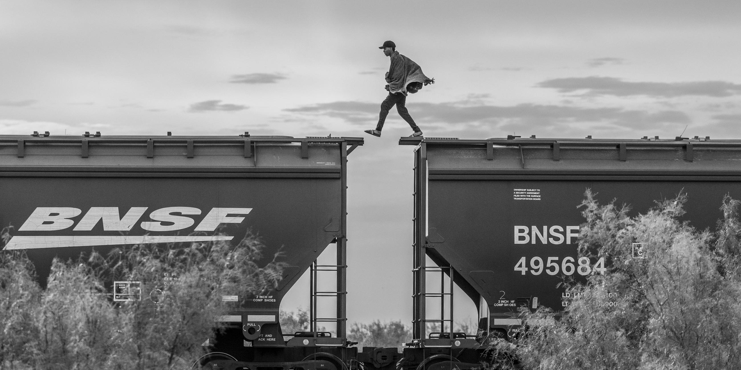 Ein Migrant läuft auf einem Frachtzug in Mexiko und überquert gerade die Lücke zwischen zwei Waggons. (8. Oktober 2023)