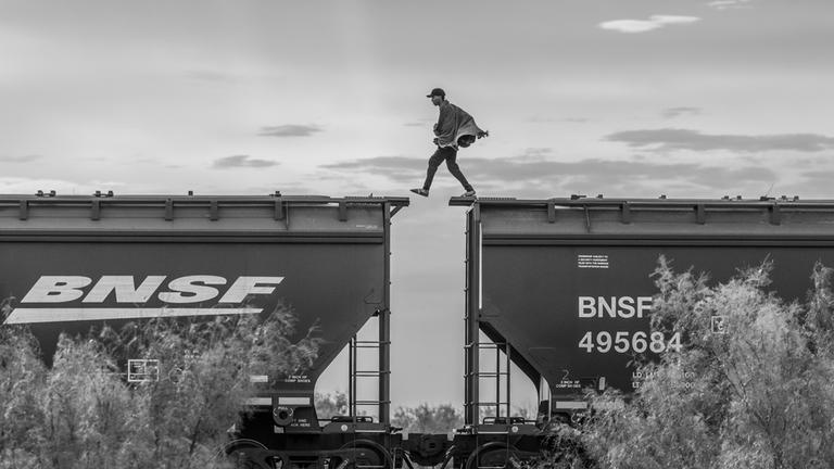 Ein Migrant läuft auf einem Frachtzug in Mexiko und überquert gerade die Lücke zwischen zwei Waggons. (8. Oktober 2023)