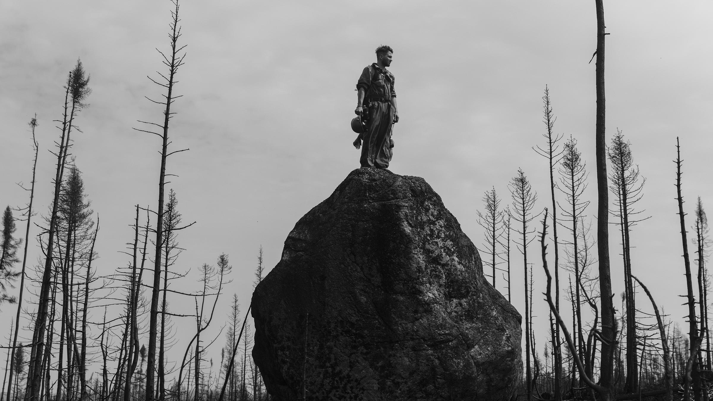 Theo Dagnaud steht auf einem Felsbrocken und blickt in den abgebrannten Wald in Quebec, Kanada (13. Juli 2023)