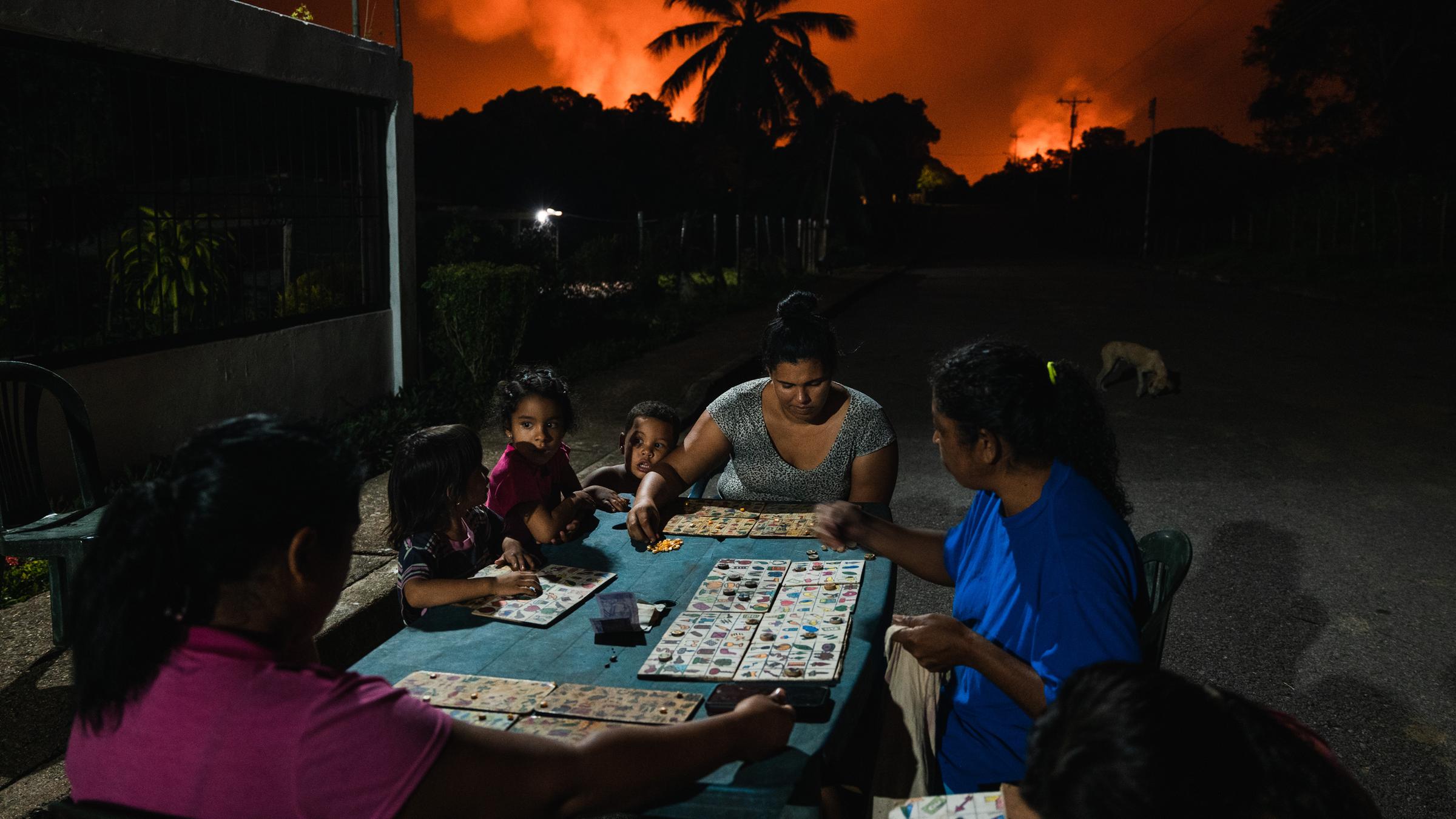 Nachbarn spielen "Tierlotto" unter einem Himmel - im Hintergrund eine der größten Gasfackeln der Welt. (5. November 2022)