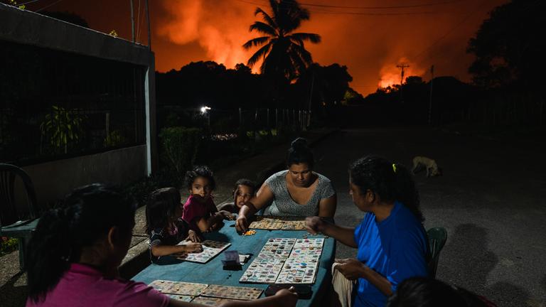 Nachbarn spielen "Tierlotto" unter einem Himmel - im Hintergrund eine der größten Gasfackeln der Welt. (5. November 2022)