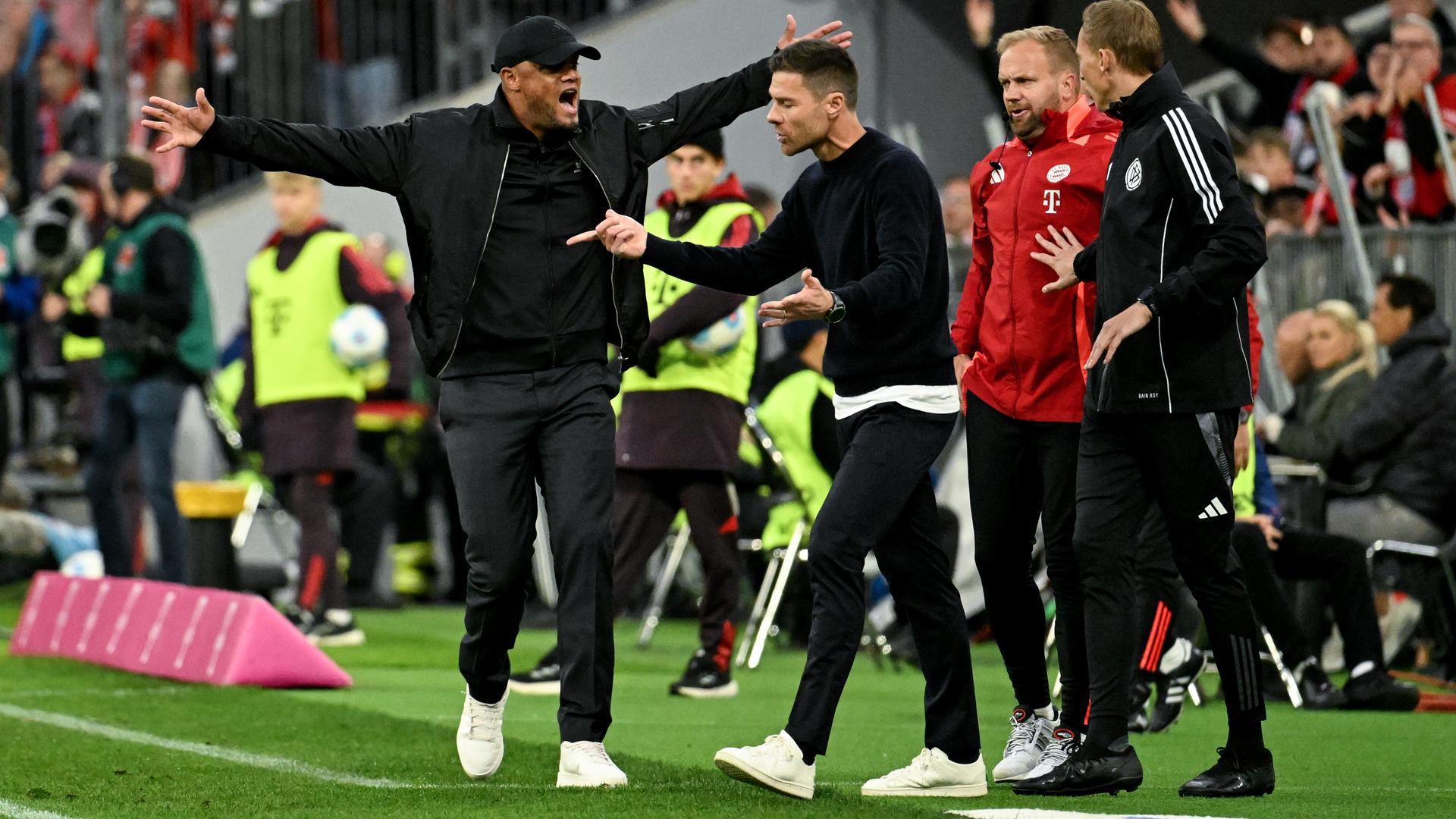 Leverkusens Trainer Xabi Alonso (2vl) und Münchens Trainer Vincent Kompany (l) gestikulieren am Spielfeldrand. 