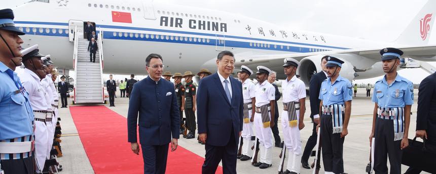 Der chinesische Präsident Xi Jinping läuft auf einem roten Teppich, im Hintergrund ist ein Flugzeug von Air China zu sehen.