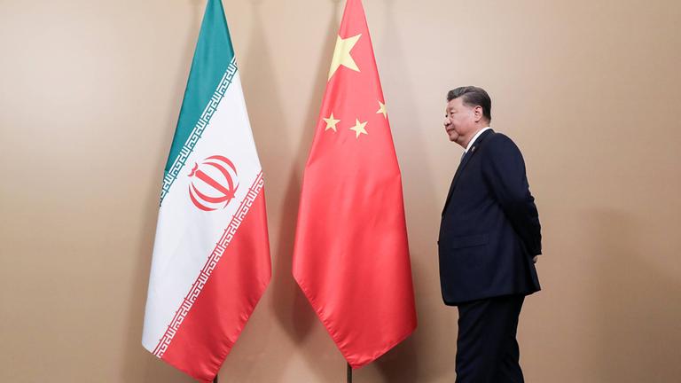 Xi Jinping Staatspräsident der Republik China steht neben Flaggen des Iran und der Volksrepublik China. (Archiv)