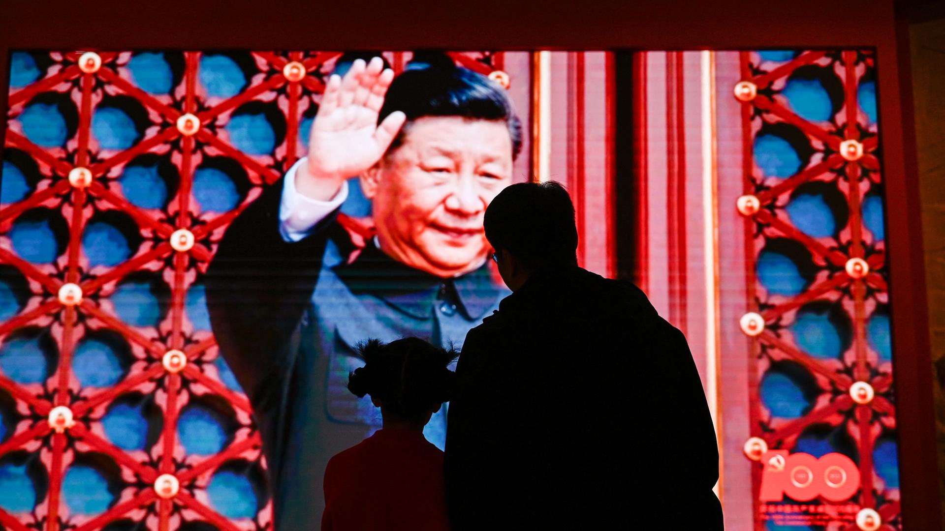 Zwei Personen schauen sich ein Video von Xi Jinping in einem Museum in Beijing an.