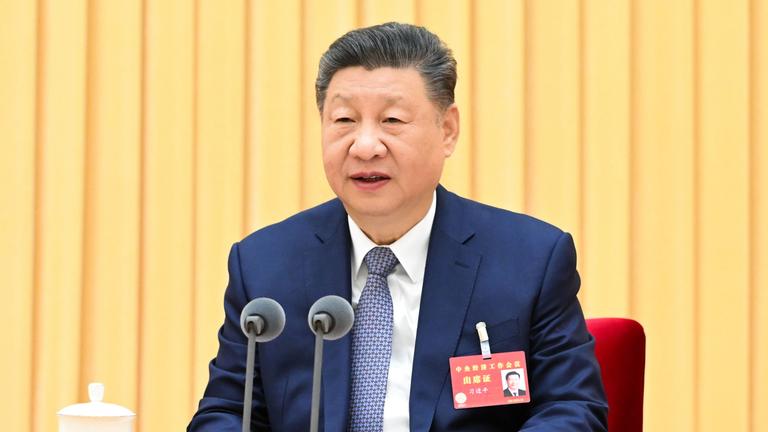 Xi Jinping sitz hinter einem Rednerpult