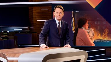 "Aktenzeichen XY... Ungelöst vom 06. Mai 2026": Rudi Cerne steht im Studio, im Hintergrund ein Bildschirm, auf dem ein Fall der Sendung abgebildet ist.