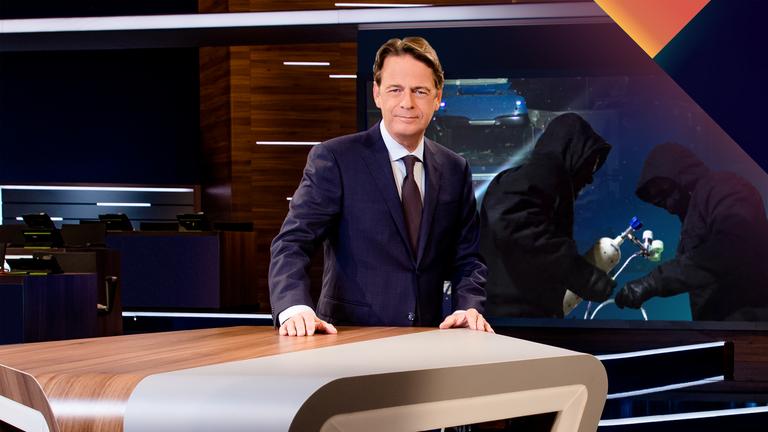"Aktenzeichen XY... Ungelöst vom 03. Mai 2026": Rudi Cerne steht im Studio, im Hintergrund ein Bildschirm, auf dem ein Fall der Sendung abgebildet ist.