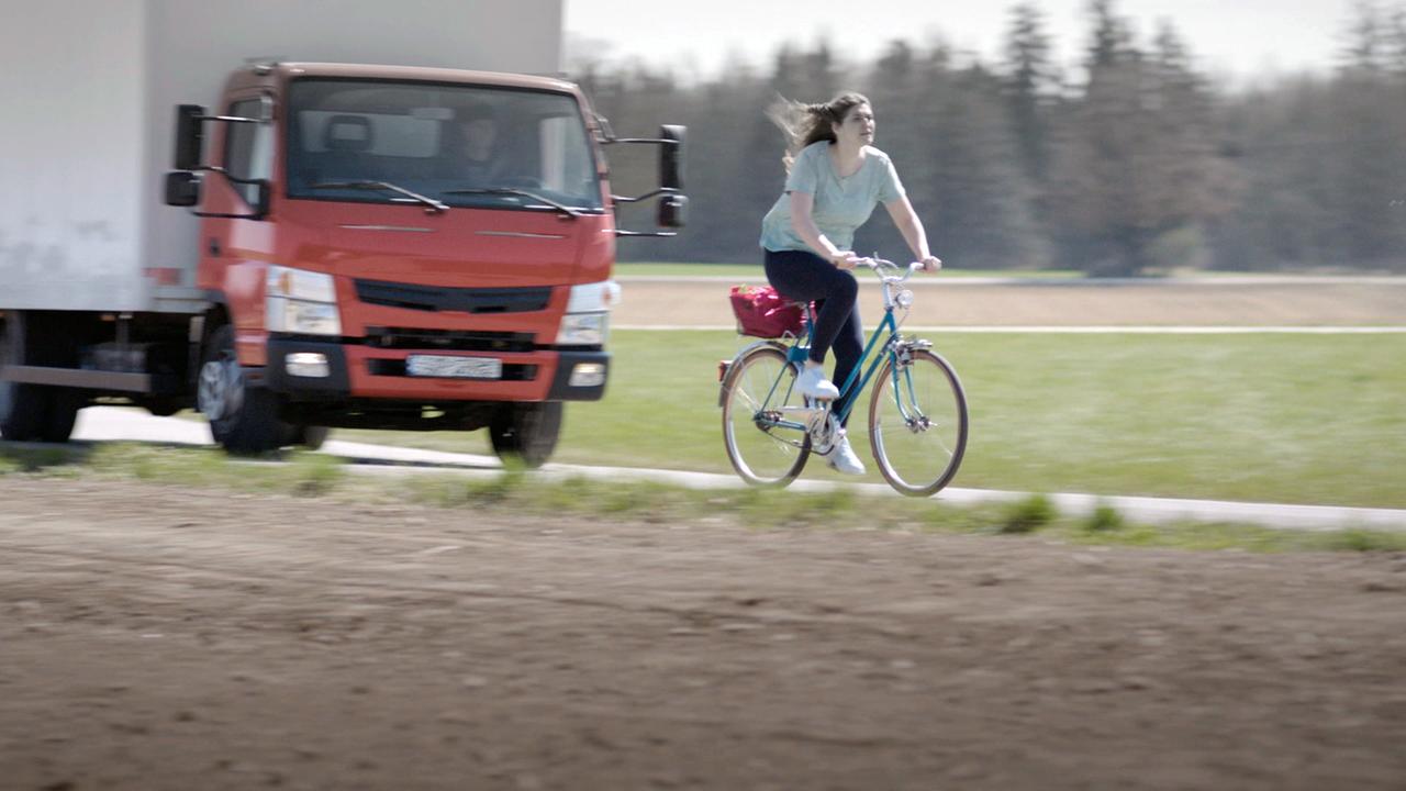 Nachgestellte Szene: Eine Frau flüchtet mit ihrem Fahrrad vor einem LKW.