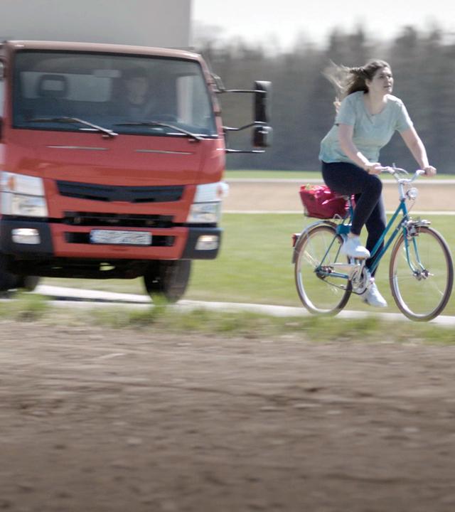 Nachgestellte Szene: Eine Frau flüchtet mit ihrem Fahrrad vor einem LKW.