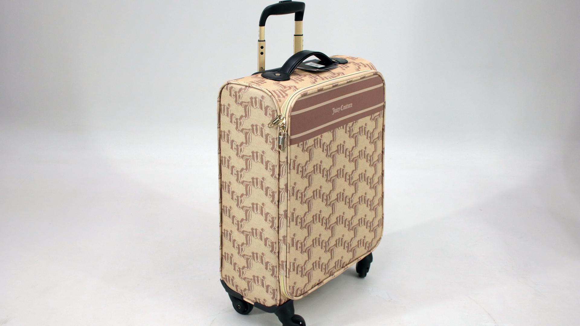 Ein Rollkoffer der Marke "Juicy Couture". Er ist beige und hat ein braunes Muster, das aus dem Logo der Marke besteht.