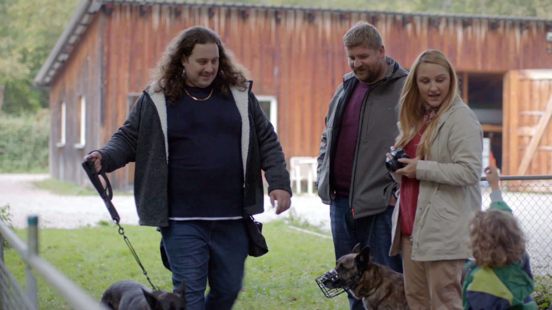 Nachgestellte Szene: Zwei Männer, eine Frau und ein Kind auf einem Hundeübungsplatz